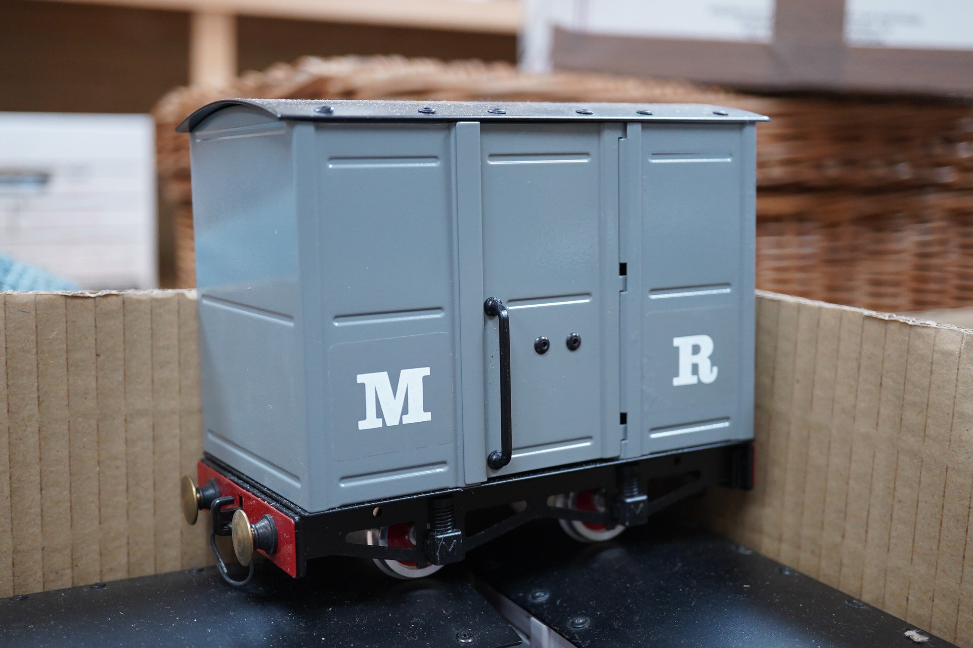 Nine Mamod narrow gauge coaches and freight wagons running on 32mm rails, comprising; three maroon painted 4-wheel coaches, two box vans, a guard’s van, two open wagons and a flatbed with log load